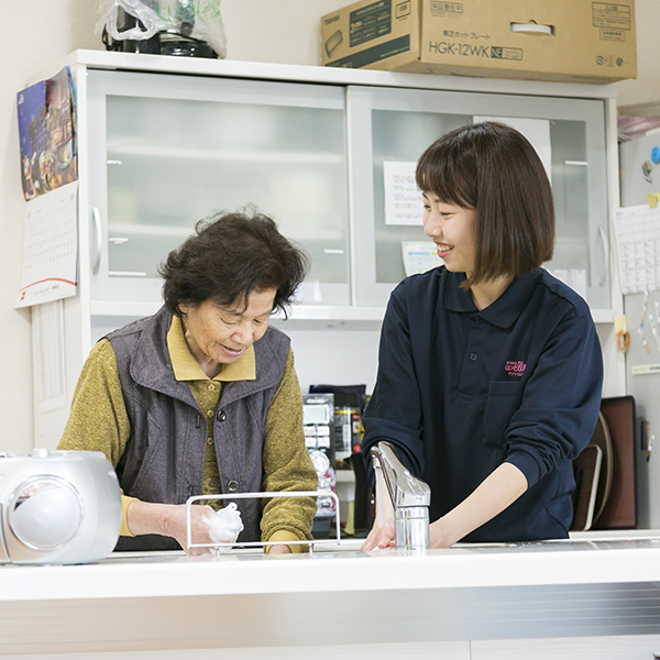 利用者さまと一緒に食器を洗っている椋田さんの写真