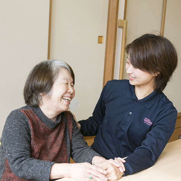 利用者さまと笑顔で談笑する高橋さんの写真